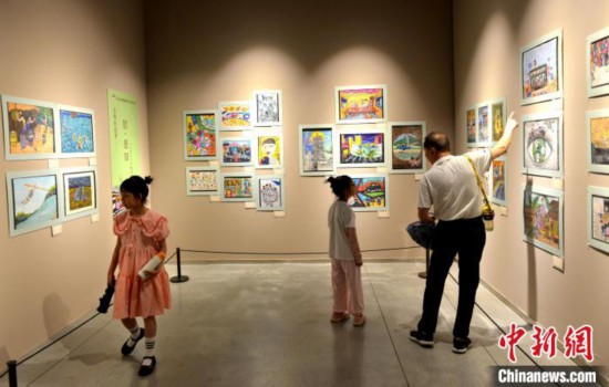图为家长带着孩子参观展览。 吕明 摄