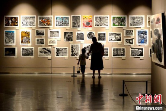 图为家长带着孩子参观展览。 吕明 摄