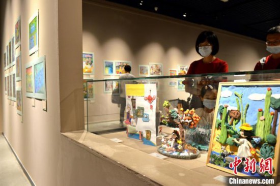 图为家长带着孩子参观展览。 吕明 摄