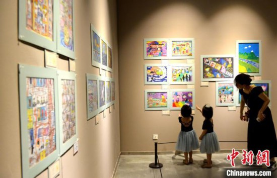 图为家长带着孩子参观展览。 吕明 摄