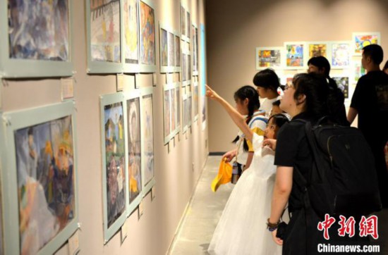 图为家长带着孩子参观展览。 吕明 摄