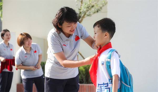 8月30日，雄安史家胡同小学学生体验学校生活。老师为学生佩戴校徽。