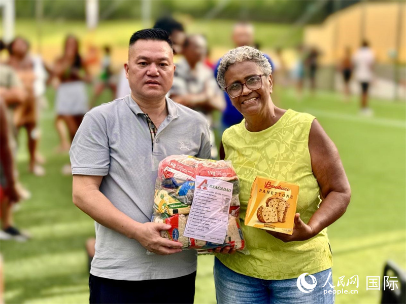  巴西中国和平统一促进会会长张小春向当地居民捐赠物品。人民网实习生 侯天泽摄