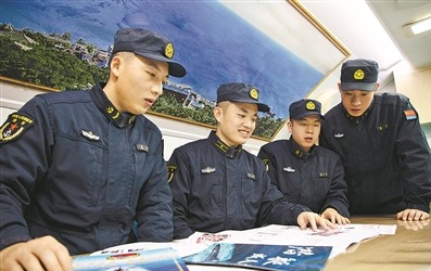 “砺刃报”主编倪呈辉（左二）与战友围看新一期“砺刃报”。 张  楠摄