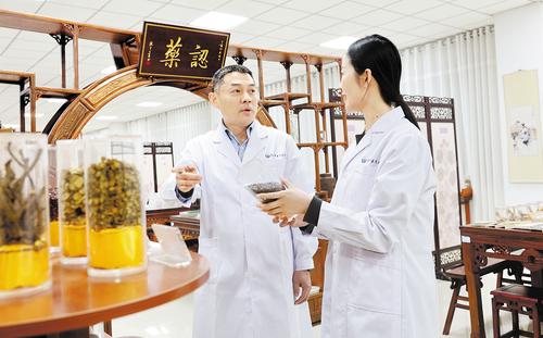 2月26日，在河北中医药大学中药文化传承基地，郭毅委员（左）与工作人员交流。本报记者 张晶摄